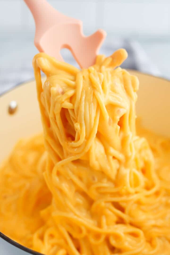 using spaghetti tongs to serve the cheesy spaghetti.