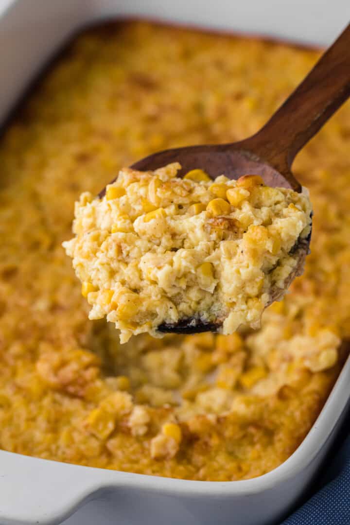 closeup of corn pudding on wooden spoon being served.