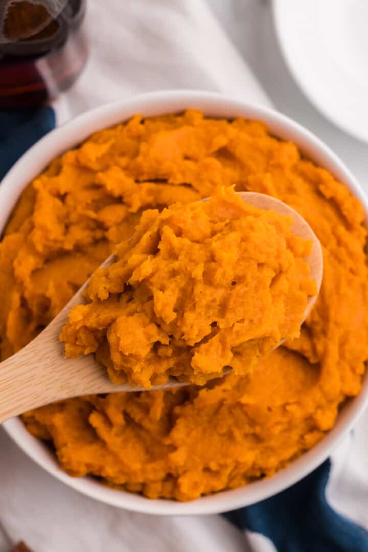 using a wooden spoon to serve the mashed sweet potatoes.