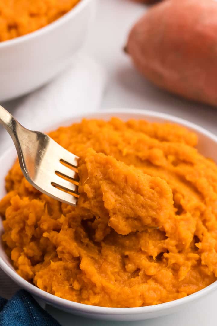 using a fork to eat the mashed sweet potatoes.