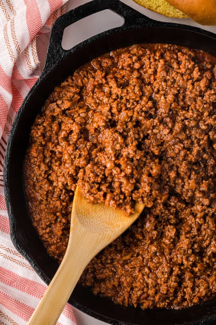 closeup of Sloppy Joes in skillet being served with a wooden spoon.