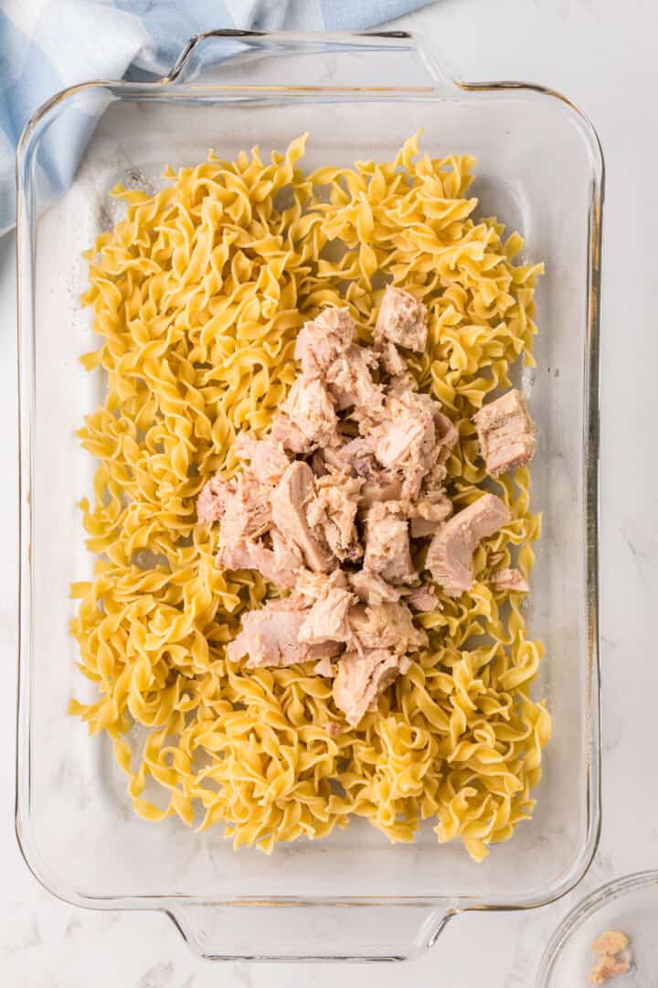 spreading the tuna with the noodles in the casserole dish.