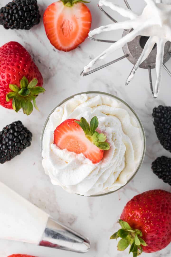 top view of a cup of whipped cream with a strawberry slice on top.