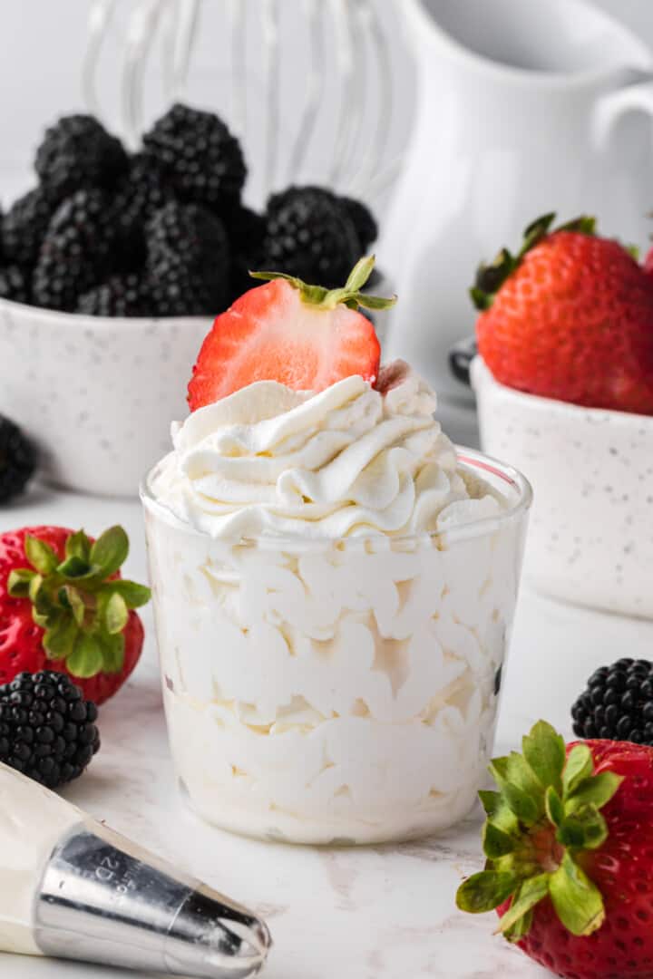 closeup of a cup of whipped cream with a strawberry one top.