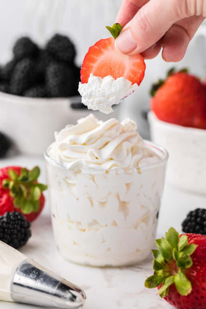 sliced strawberry dipped into the cup of whipped cream.