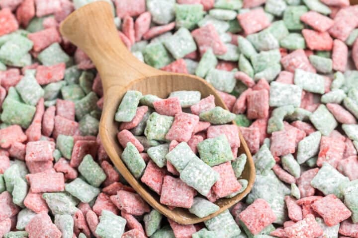 large pile of Christmas Muddy Buddies with small wooden scoop in it.