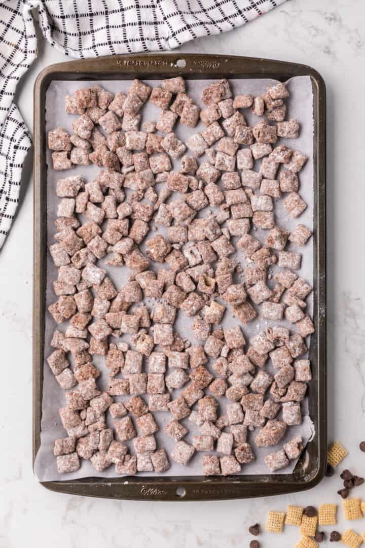 Muddy Buddies on baking sheet with parchment paper to dry.