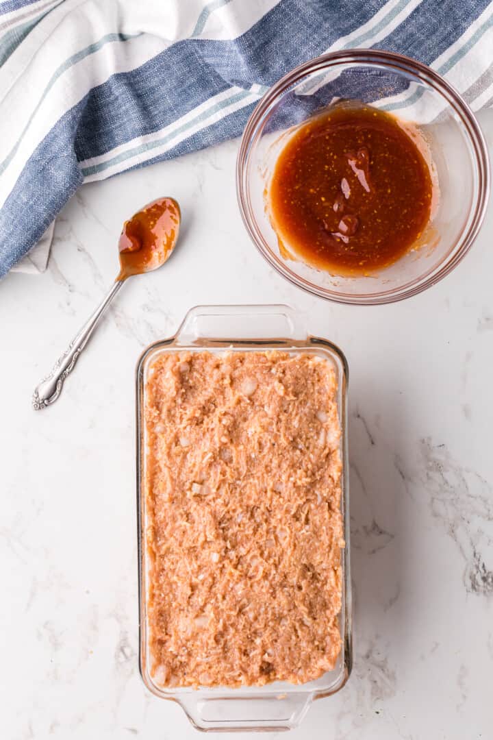 chicken meatloaf in pan with sauce on side in the a bowl.