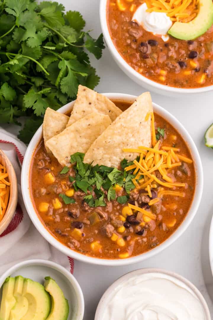 Creamy Taco Soup in white bowl topped with tortilla chips.