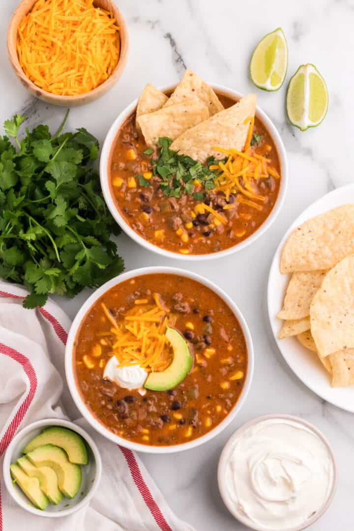 two bowls of creamy taco soup with toppings.