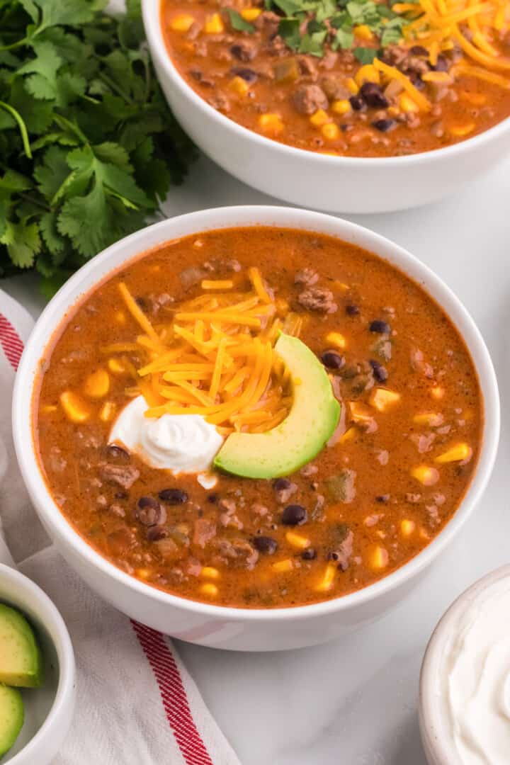 closeup of the taco soup topped with sour cream, cheese and an avocado slice.