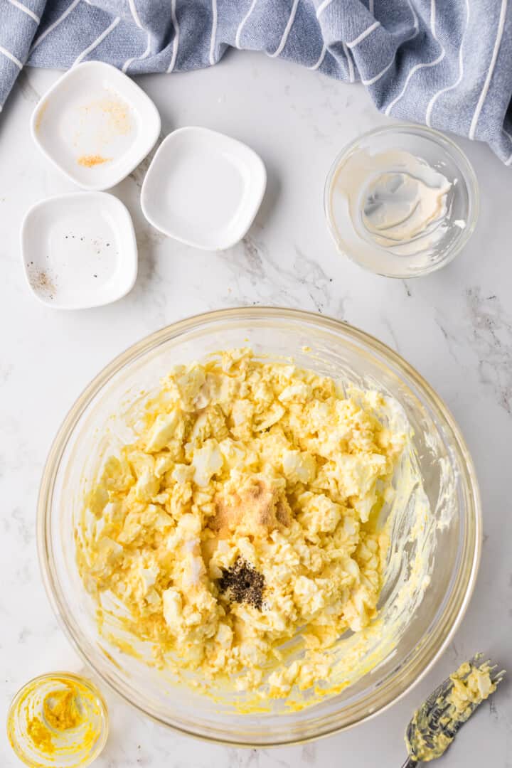 seasoning the egg salad in a large glass bowl.
