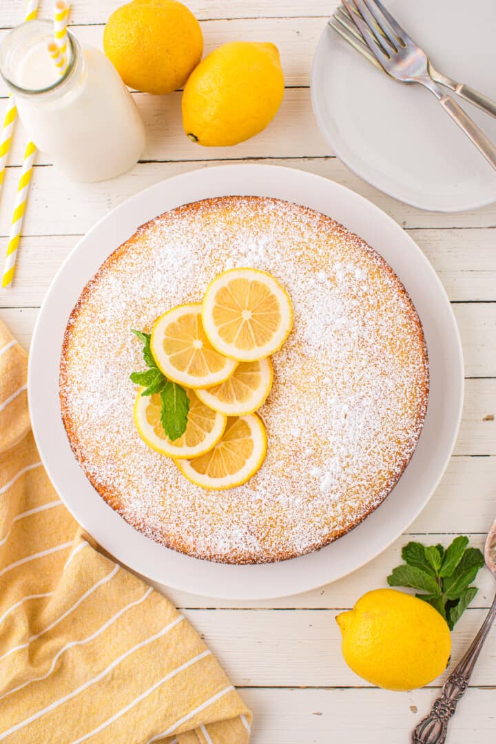 lemon ricotta cake topped with powdered sugar and lemon slices.