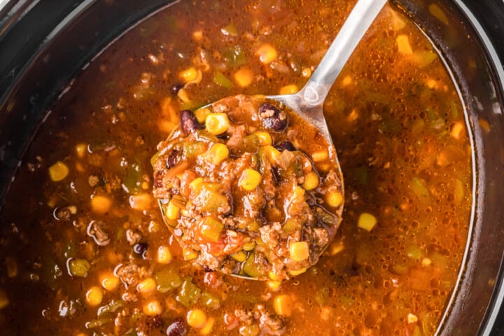 using a ladle to serve the taco soup out of the slow cooker.