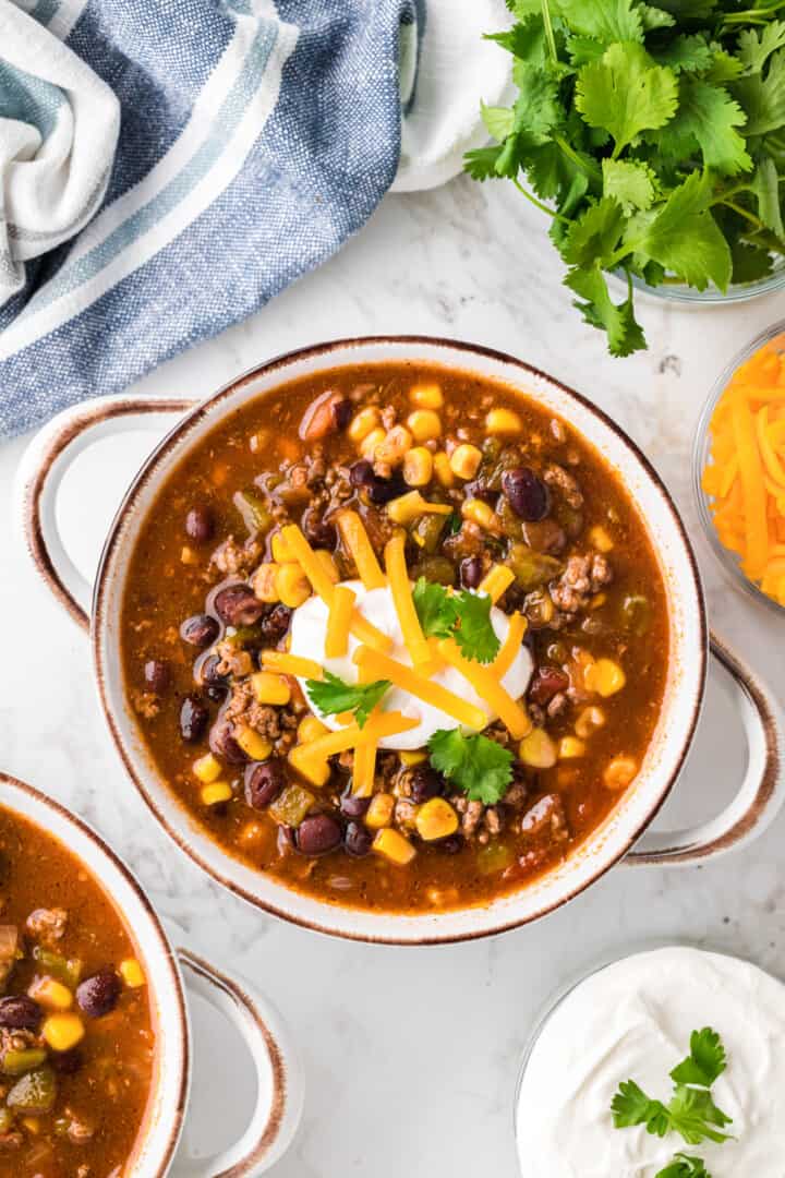 Slow Cooker Taco Soup in serving bowl topped with cheese and sour cream.