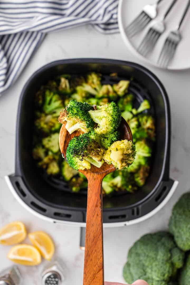 air fried broccoli being served with a wooden spoon.