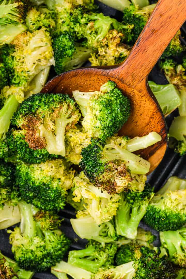 air fryer broccoli being served with a wooden spoon.