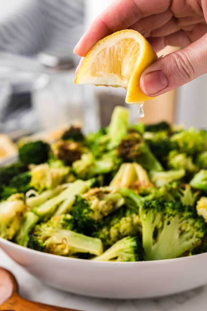 spritzing some lemon juice on top of broccoli.