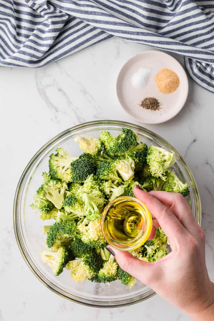 adding the oil to the broccoli for the seasoning.