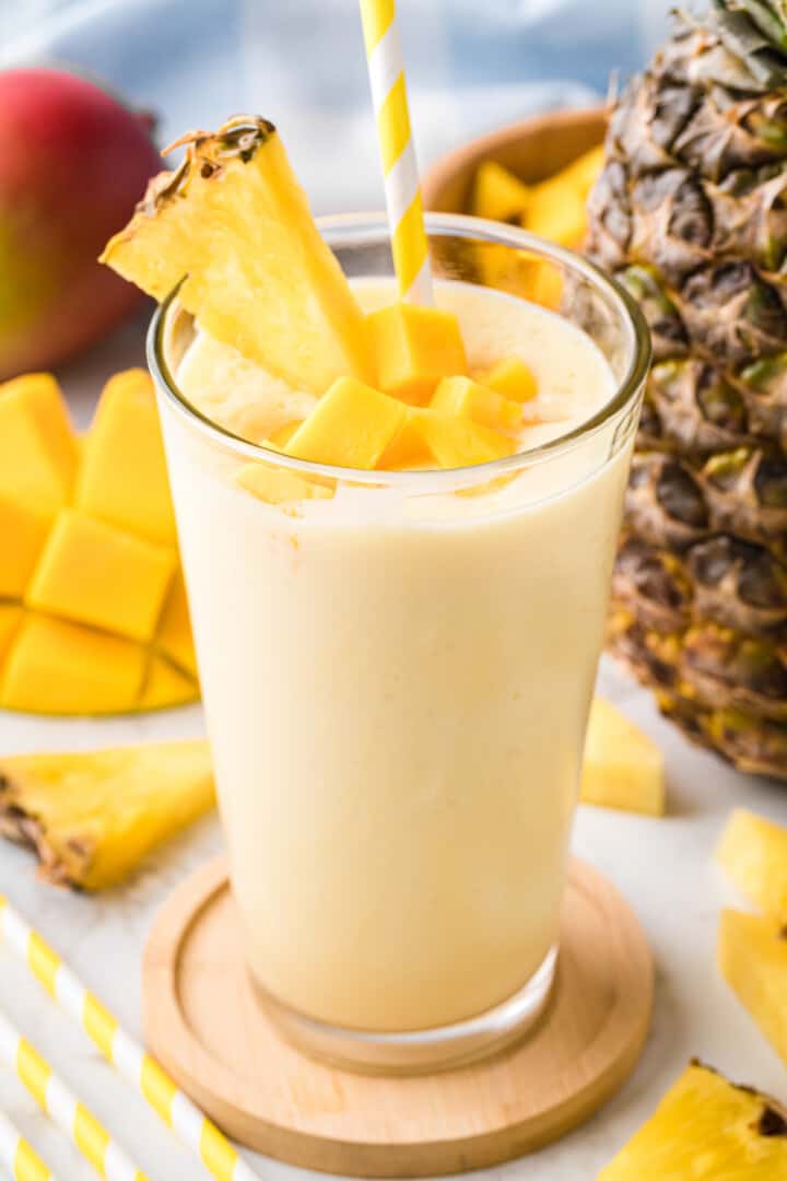 Mango Pineapple Smoothie in glass on wooden coaster.