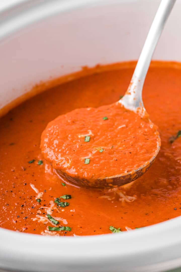 using a ladle to serve the tomato soup.