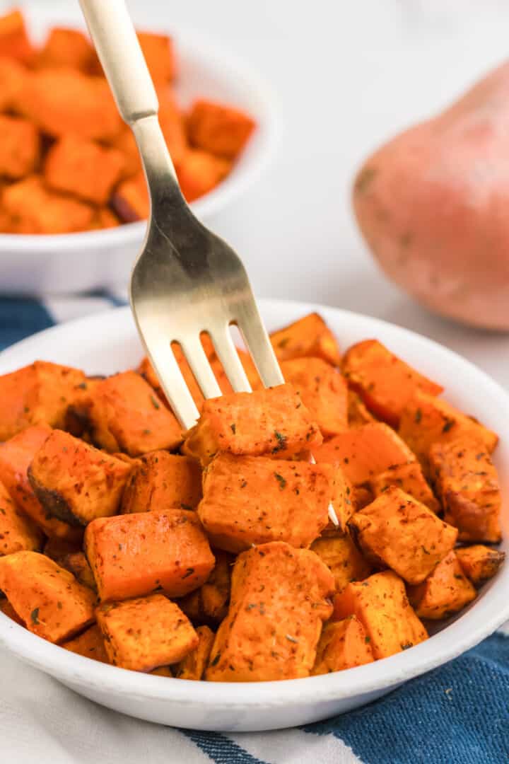 air fryer sweet potatoes in white bowl serving with fork.