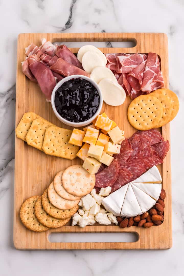 adding the crackers to the charcuterie board.