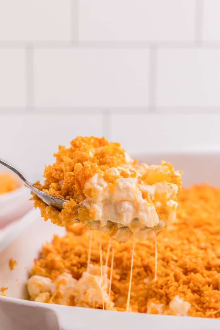 Funeral Potatoes being served out of white casserole dish.