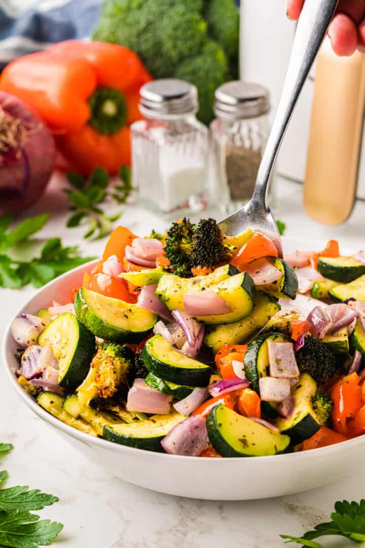 serving the air fryer vegetables from the white bowl.