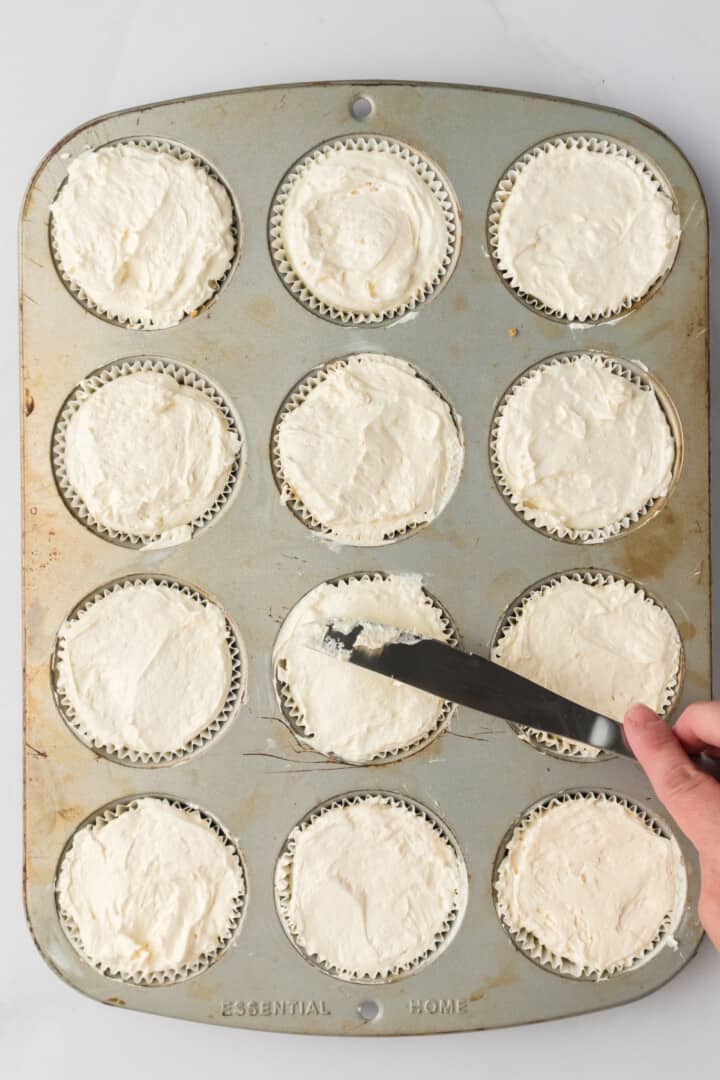 filling the muffin liners with the cheesecake filling.