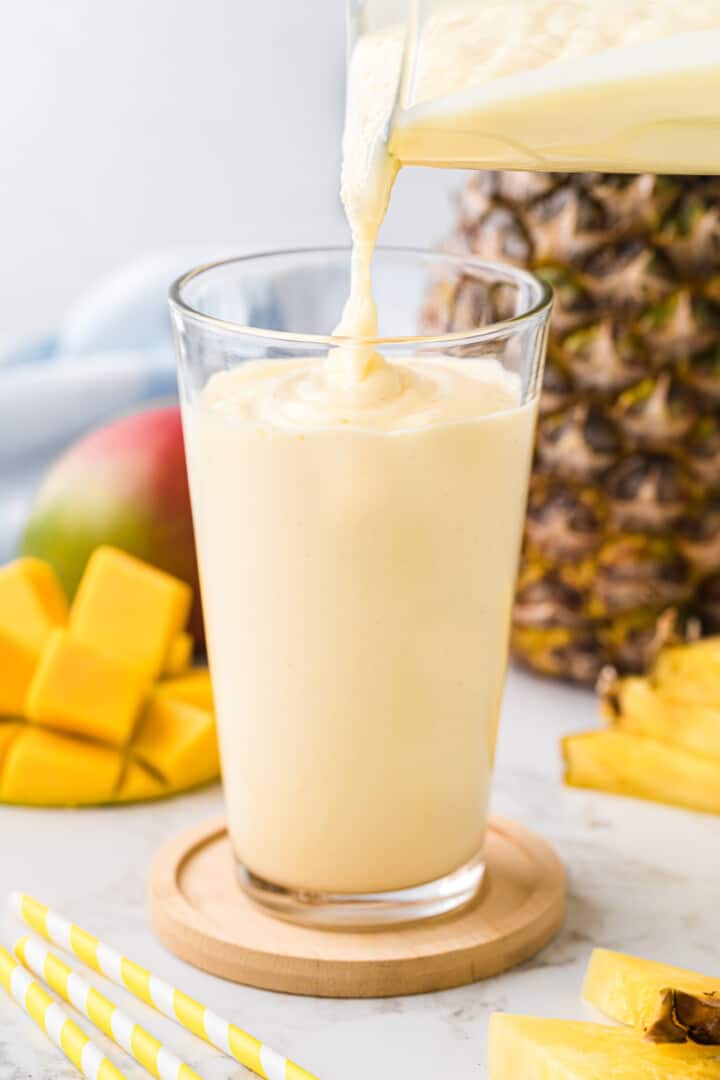 pouring the smoothie from the blender into a glass.