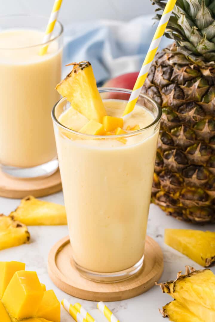 Mago Pineapple Smoothie garnished with fresh mangoes and a pineapple slice.