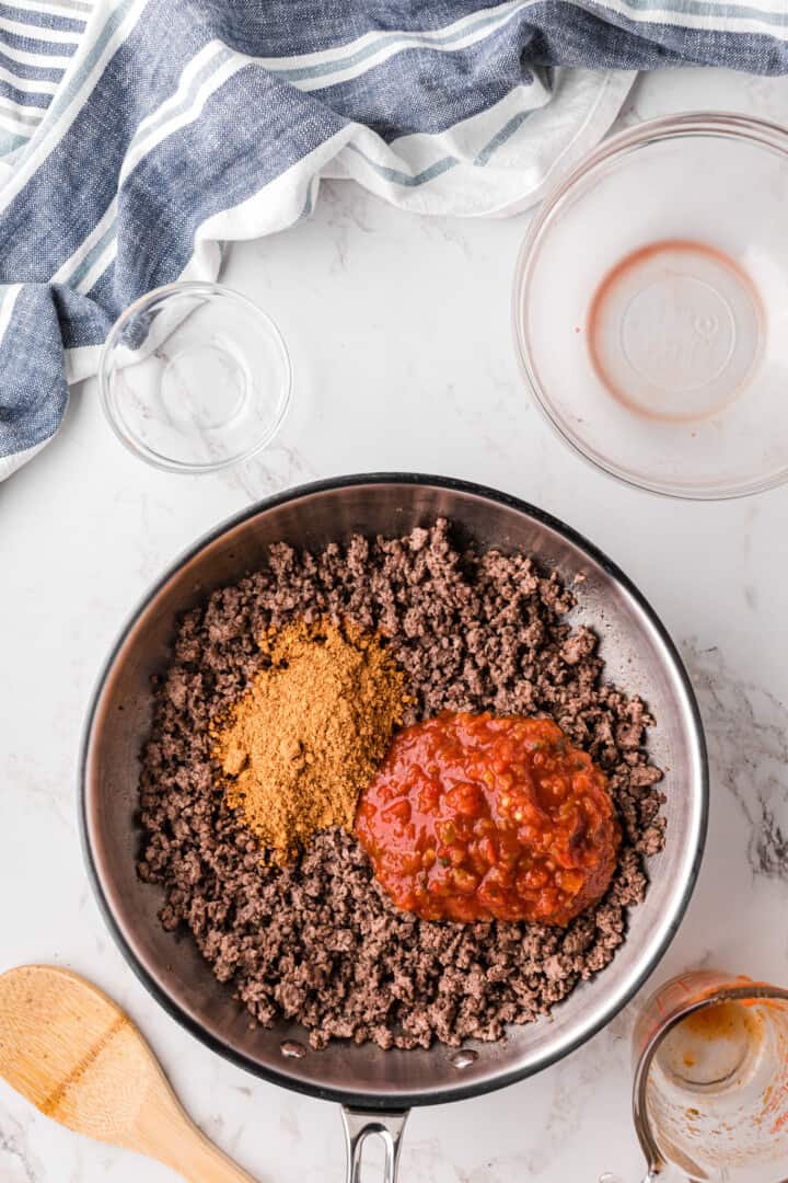 adding the salsa and taco seasoning to cooked ground beef.