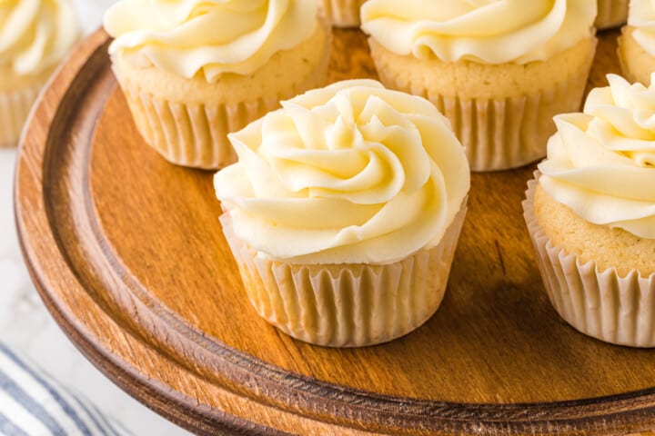 iced cupcakes on a wooden serving tray.