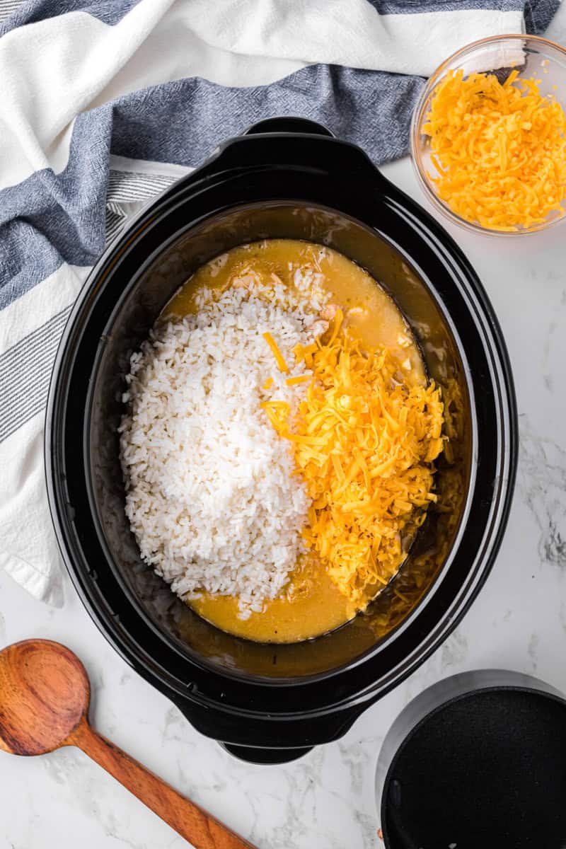 adding the rice and cheese to the slow cooker.