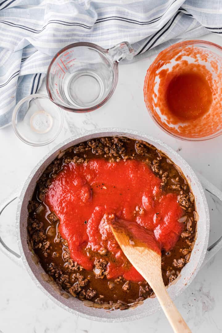 adding the tomato sauce, vinegar and water to the make the chili.