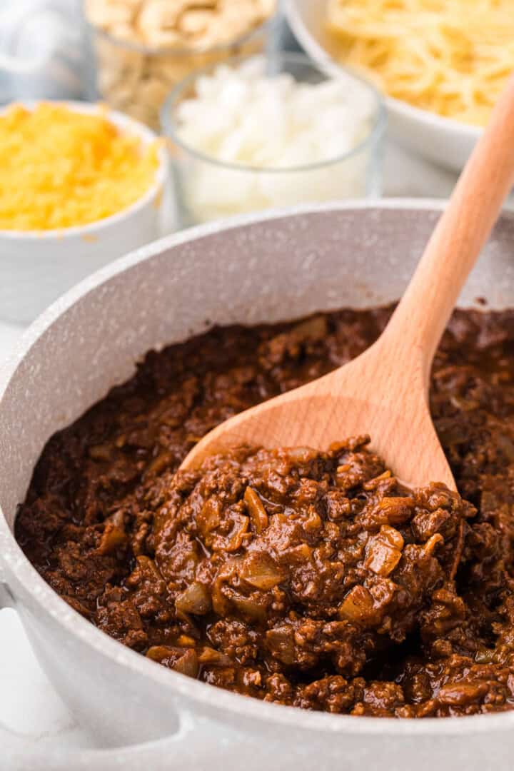 serving the chili with a wooden spoon.