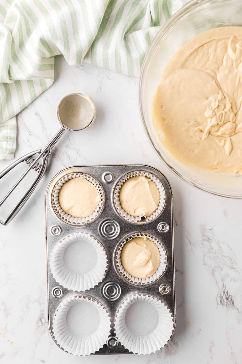 scooping the cupcake batter into the cupcake liners in the pan.