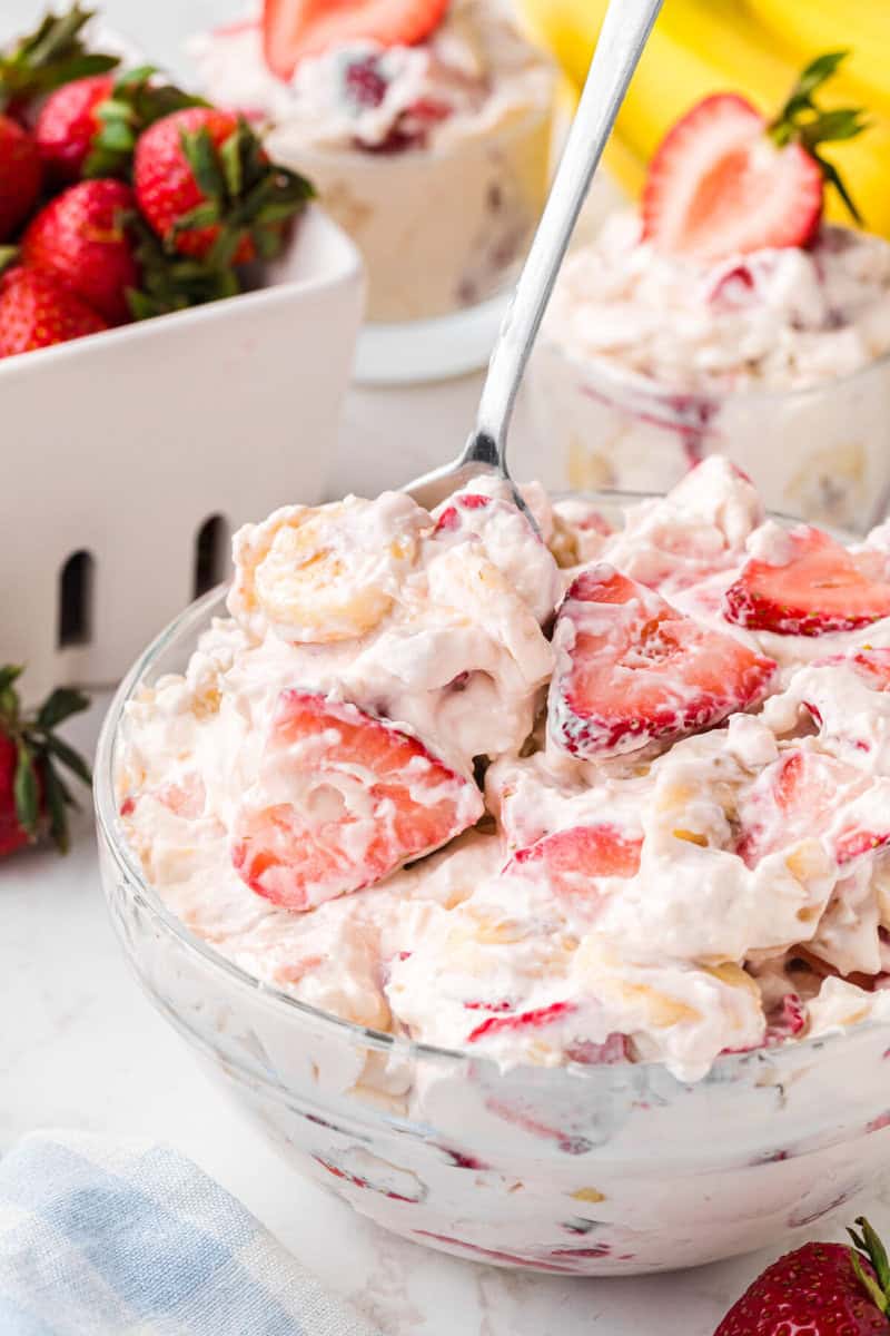 serving the Strawberry Banana Cheesecake Salad out of the glass bowl.