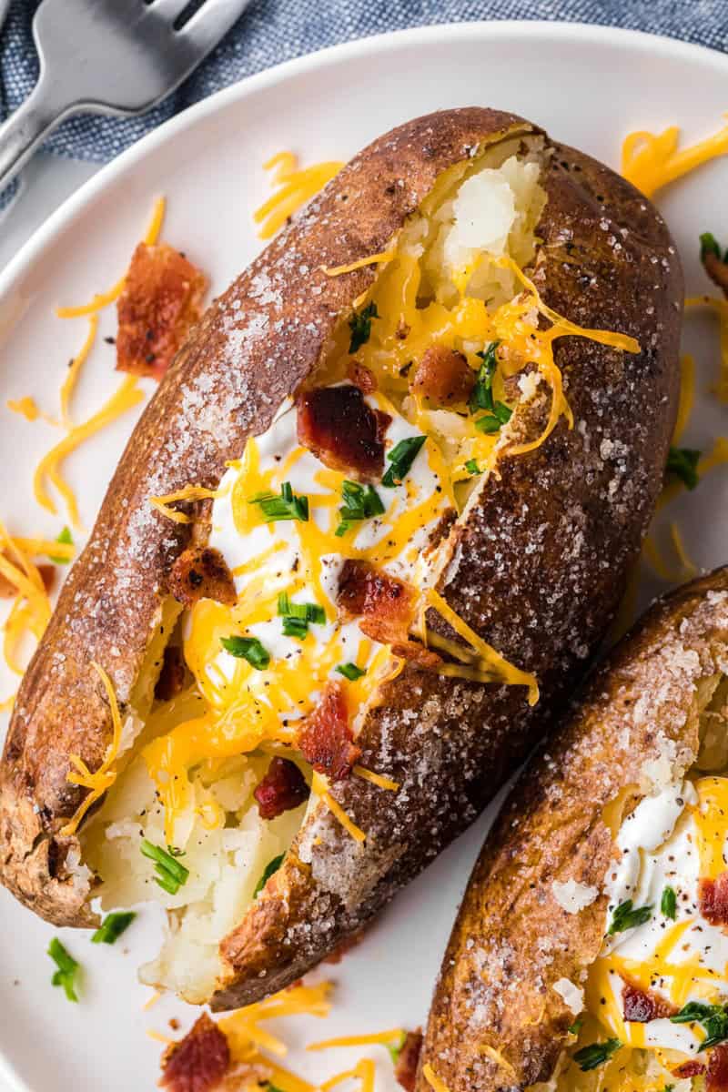 closeup of baked potato loaded with sour cream, cheese and bacon.