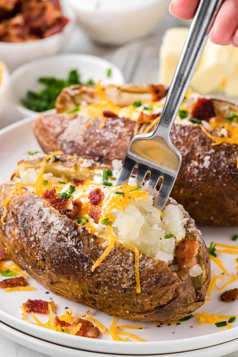 using a fork eat the baked potato.