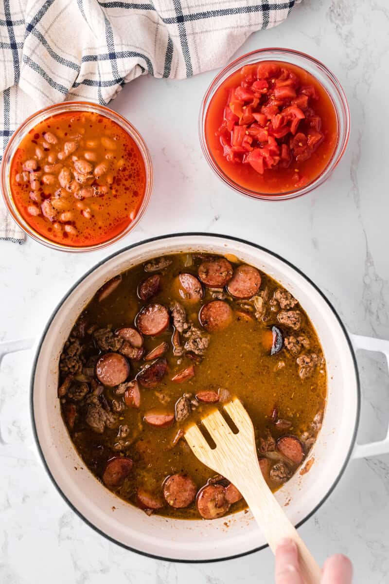 adding the broth to the pot with the beans and tomatoes on the side.