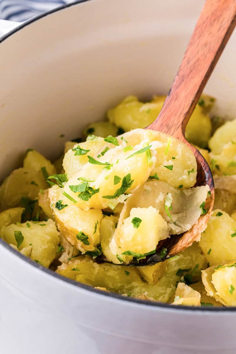 using a wooden spoon to serve the potatoes.