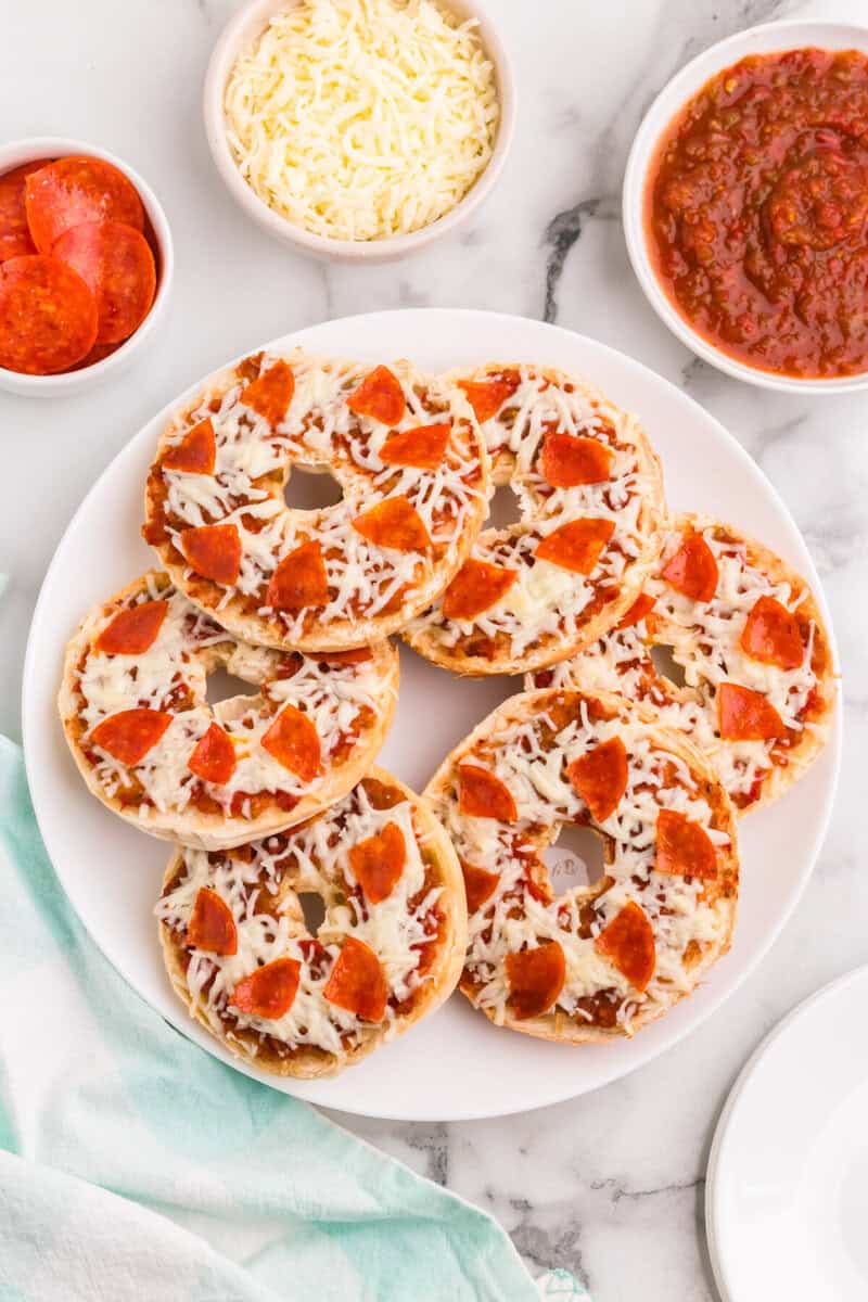 top down view of pizza bagels on white serving plate.