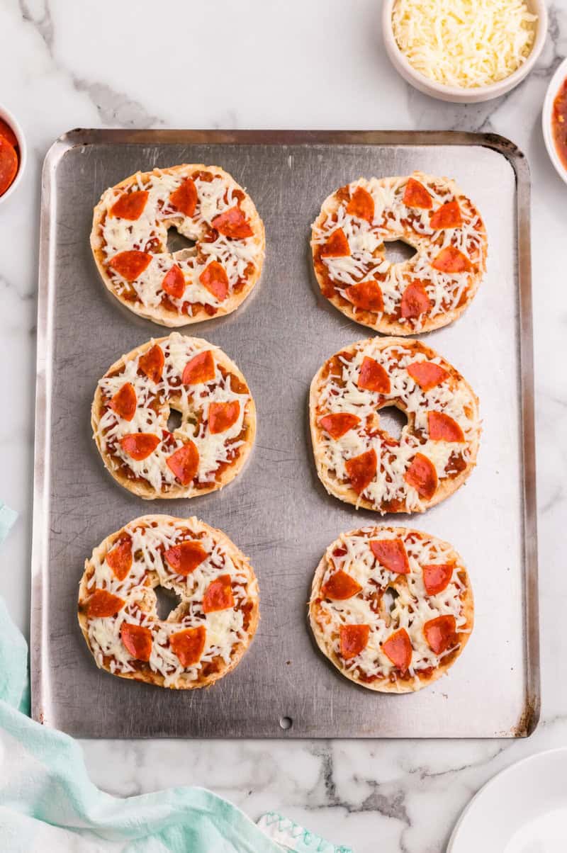 pizza bagels on a baking tray.
