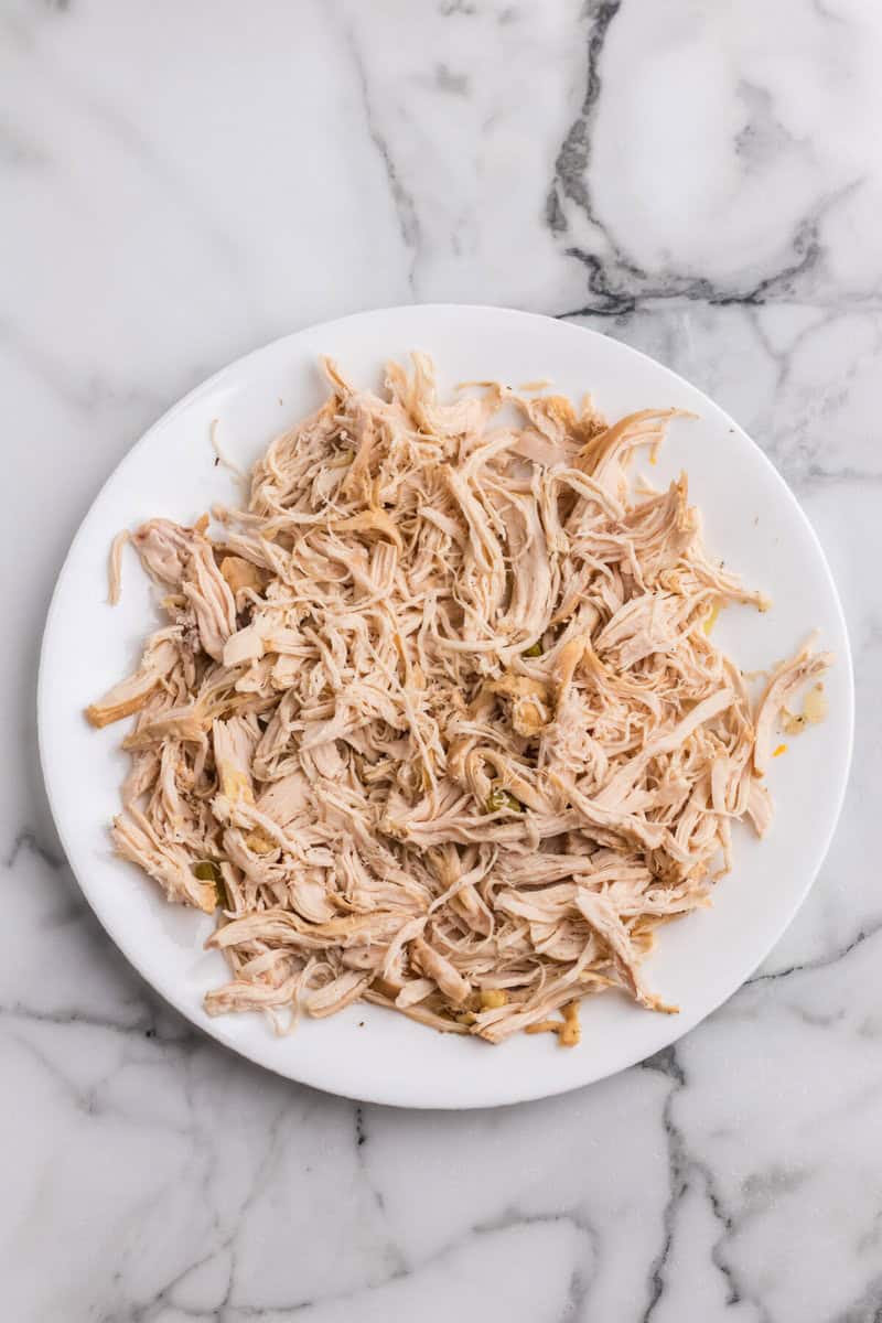 chicken shredded on white plate for the soup.