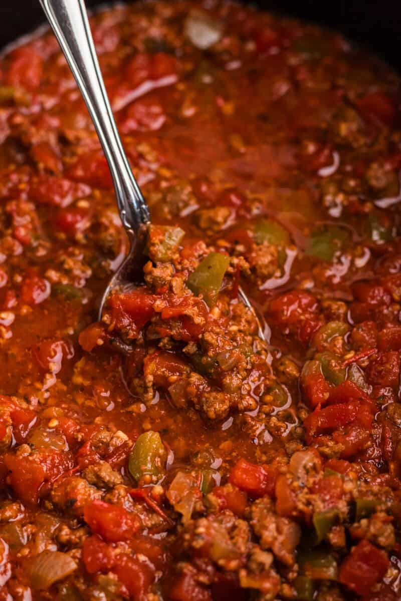 using a spoon to serve the spaghetti sauce.