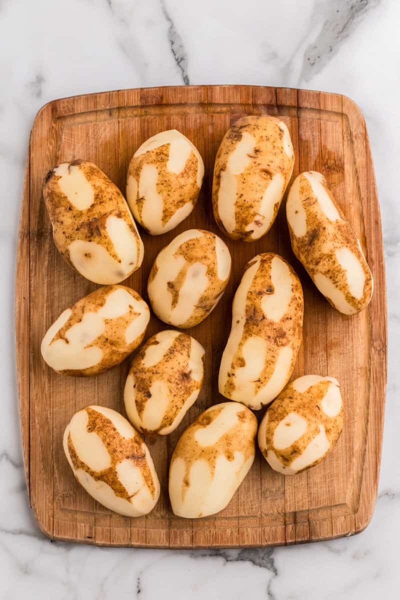 potatoes washed and peeled on cutting board.