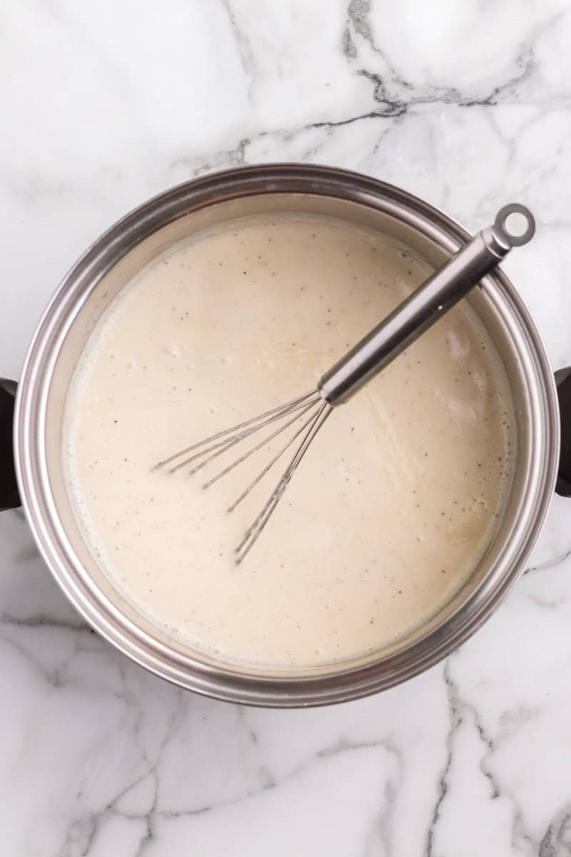 whisking the cheese sauce in the pot.