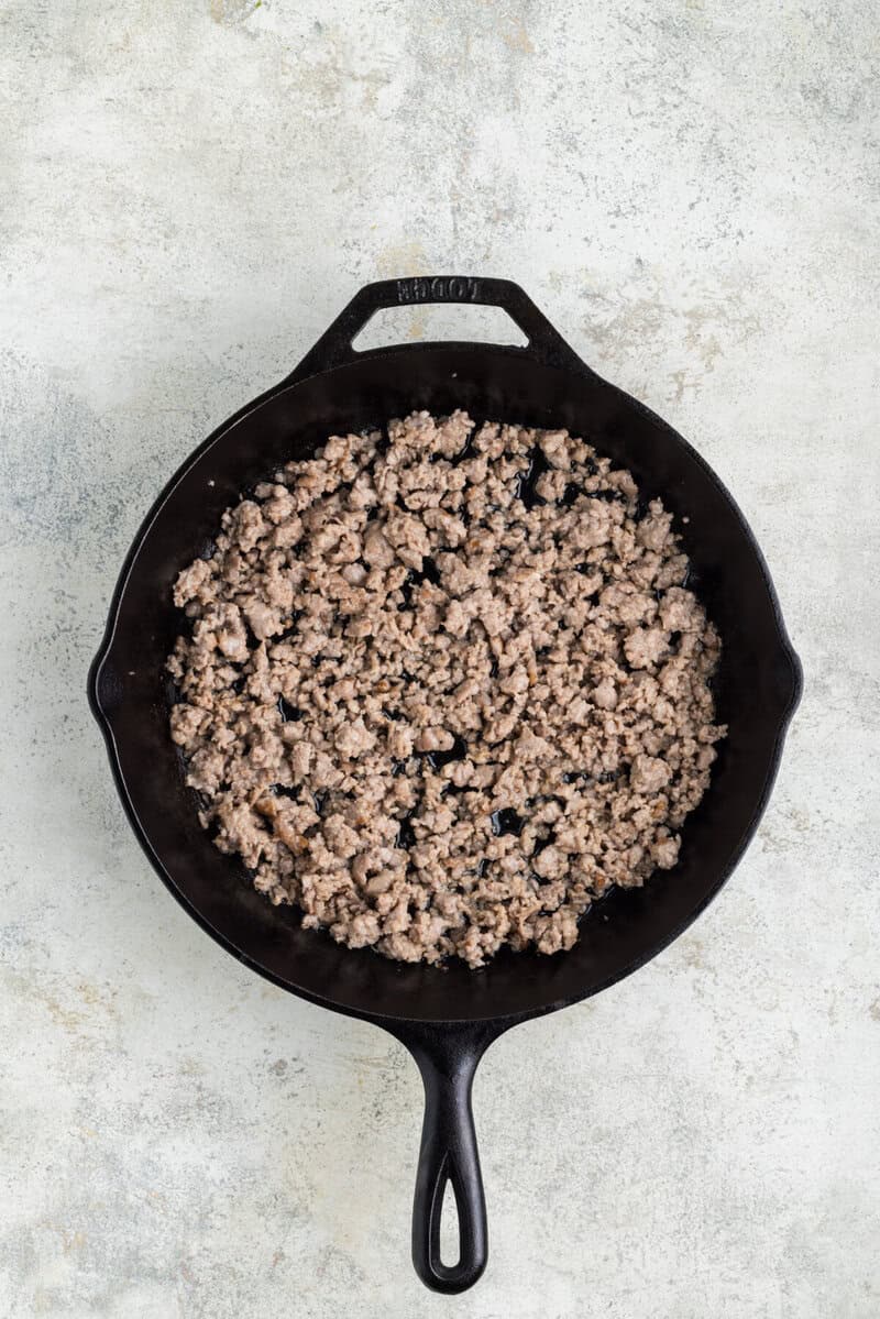 cooking the sausage in a skillet.